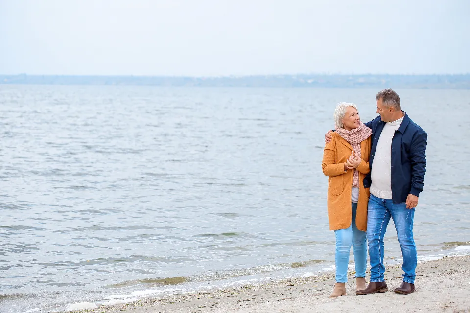 Couple de seniors souriant, se promenant au bord de l'eau