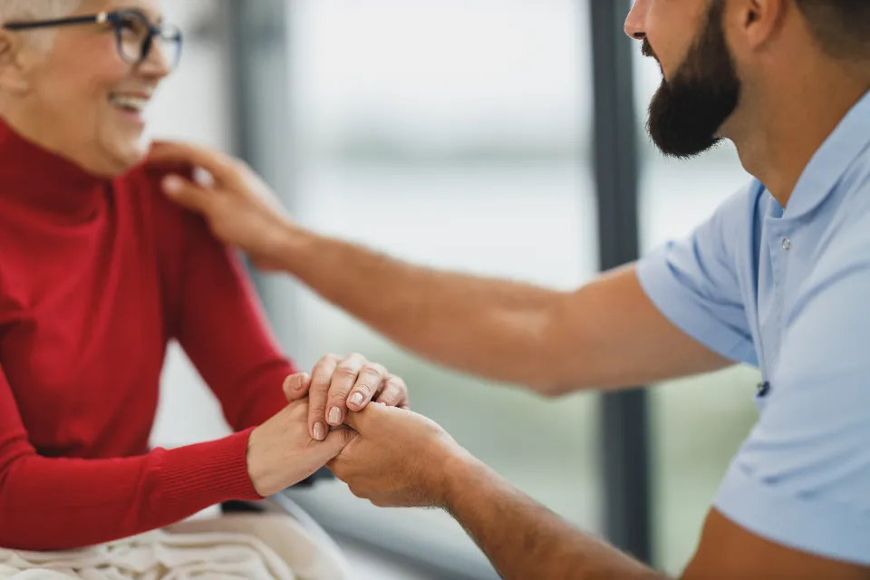 Soignante tenant la main d'une patiente âgée, dans le calme